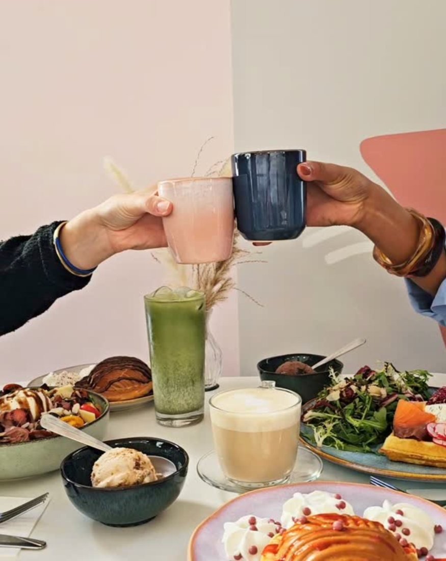 Deux tasses qui trinquent au-dessus d'une table de brunch
